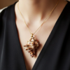 pendentif Coquillage beige clair avec pointes orné de perles dorées et grenats avec une bélière dorée porté sur une courte chaine dorée par une femme dont on ne voit que le buste et qui porte une robe noire col V