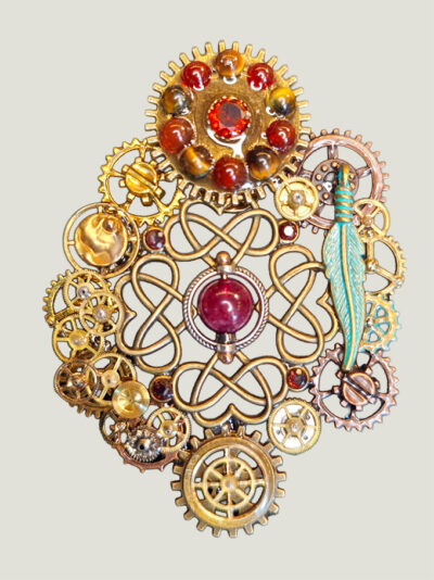 recto Broche composée d’engrenages coeurs et plume verte en alliage, ornée de 5 Grenats, 10 Agates rouges et marron et 1 Calcédoine  montée sur un axe