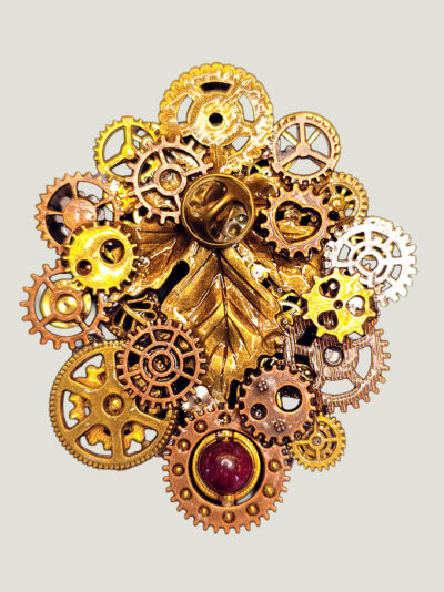 Versod'une Broche composée d'engrenages et pièces en alliage ton dorés et cuivre avec une perle calcédoine montée sur un axe