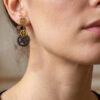 Boucles d'Oreilles composées de 5 engrenages collés verticalement portée sur l'oreille droite d'une femme brune au cheveu long attachés dont on ne voit que le bas du visage