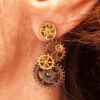 Boucles d'Oreilles composées de 5 engrenages collés verticalement portées par une femme rousse sur l'oreille gauche