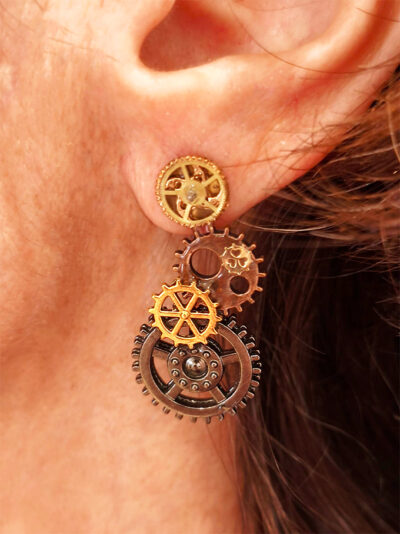 Boucles d'Oreilles composées de 5 engrenages collés verticalement portées par une femme rousse sur l'oreille gauche