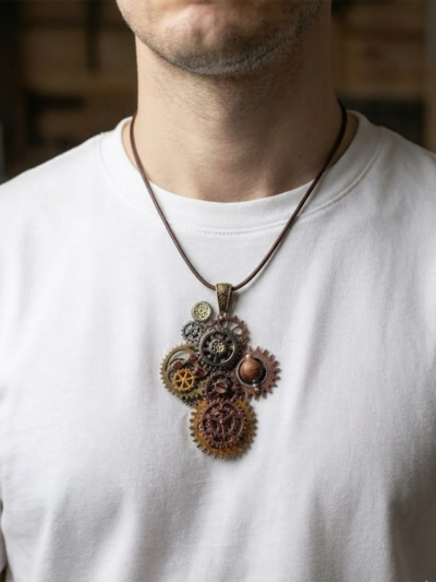 Pendentif composé d’engrenages alliage, orné de 2 Grenats et d'une Agate marron montée sur un axe avec une bélière gravée de couleur bronze porté avec un cordon court en cuir foncé par un homme dont on ne voit que le buste et qui porte un tee shirt blanc
