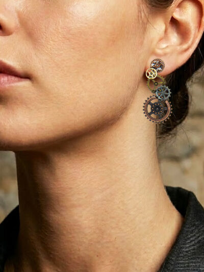 Boucles d'Oreilles composées de 5 engrenages collés verticalement portée sur l'oreille gauche d'une femme brune au cheveu long attachés dont on ne voit que le bas du visage