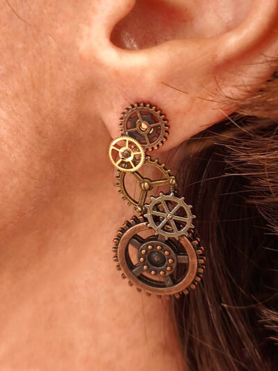 Boucles d'Oreilles composées de 5 engrenages collés verticalement portées sur l'oreille gauche par une femme rousse dont on ne voit que l'oreille et le bas du visage