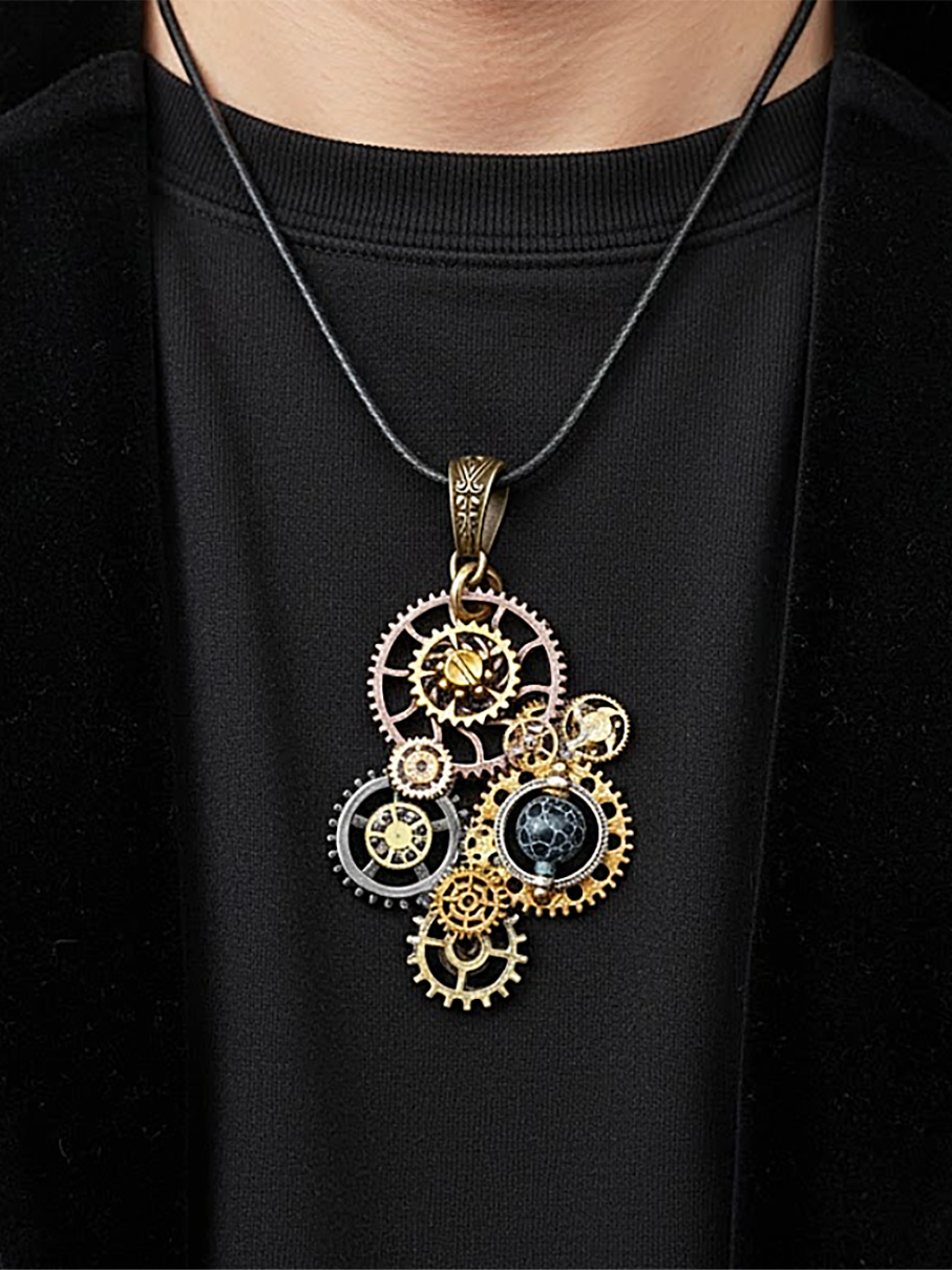 Pendentif composé d’engrenages alliage, orné d'une Agate bleu montée sur un axe avec une bélière gravée de couleur bronze porté avec un cordon mi-long en cuir foncé par un homme dont on ne voit que le buste et qui porte un tee shirt noir