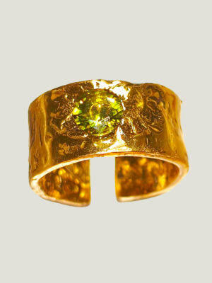 vu de dessus d'une bague anneau large en laiton doré réticulé avec une pierre verte sur le dessus au centre