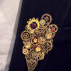 Recto Broche composée d'engrenages et de pièces en alliage aspect laiton vieilli ornée de 4 beaux grenats naturels, petites perles dorées Agates et calcédoine montée sur un axe porté sur une veste en velours noir