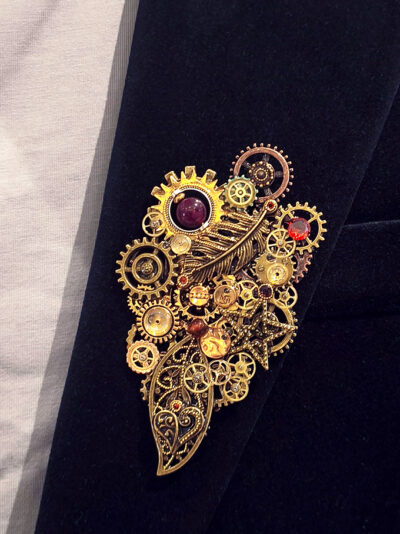 Recto Broche composée d'engrenages et de pièces en alliage aspect laiton vieilli ornée de 4 beaux grenats naturels, petites perles dorées Agates et calcédoine montée sur un axe porté sur une veste en velours noir