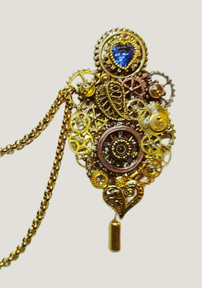 Recto Broche duo Steampunk composée d'engrenages et d'éléments divers (dont une grande feuille) en alliage de bronze reliées par une double chaîne et ornées de petites perles dorées et d'un cristal bleu véritable.