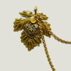 Recto Broche duo Steampunk composée d'engrenages et d'éléments divers (dont une grande feuille) en alliage de bronze reliées par une double chaîne et ornées de petites perles dorées et d'un cristal bleu véritable.