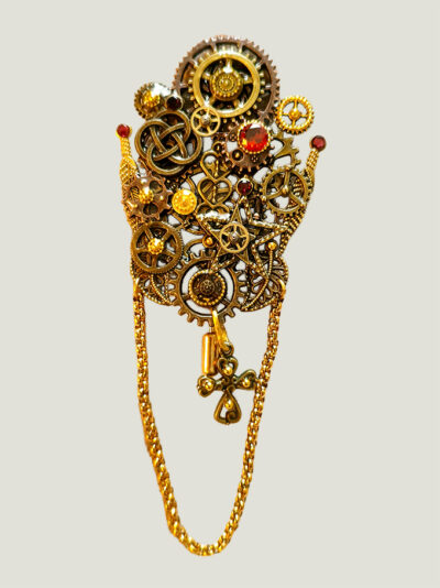 recto Broche Steampunk composée d'engrenages et d'éléments divers en alliage bronze. Ornée de 5 grenats de petites perles dorées et d'une chaîne