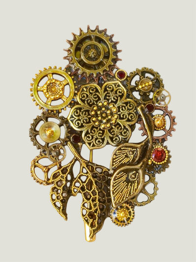 recto Broche Steampunk composée d'un engrenages et d'éléments divers en alliage bronze Ornée de 4 grenats et de petites perles dorées.